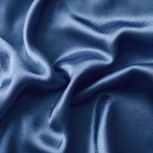 Silver silk background with a folds. Abstract texture of rippled silk surface